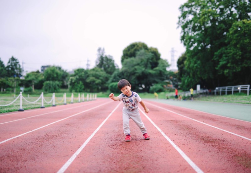 陸上トラックでヨーイドンの構えをする男の子