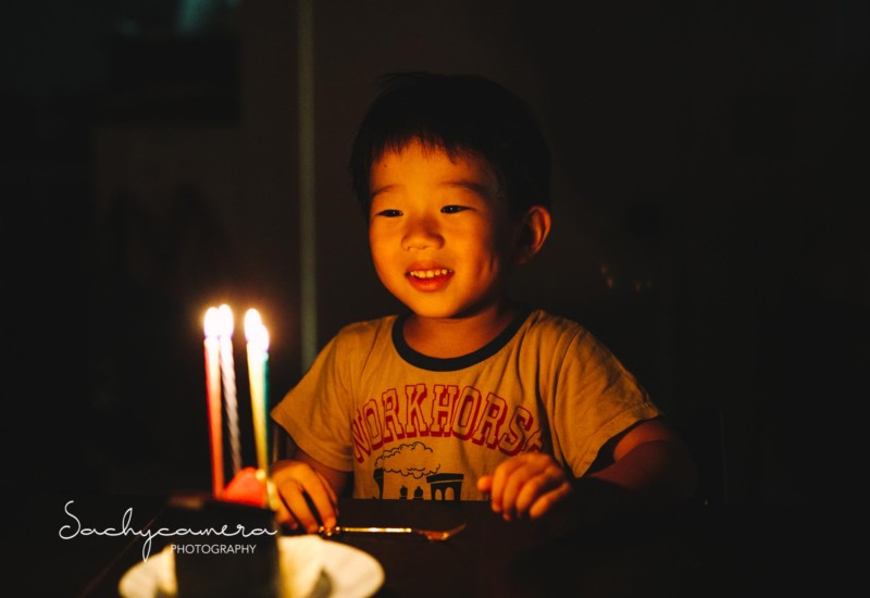 誕生日ケーキのロウソクを見つめている